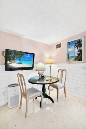 A room with a television displaying a beach scene, a table with chairs, a lamp, and a heater. - 2 BR/2 BA Beach Front Suite-Kayaks-SUPs-Bikes-Pets (Englewood)