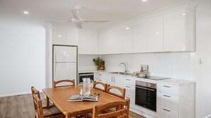 Una cucina moderna con mobili bianchi, un tavolo da pranzo con sedie e una ventola a soffitto.