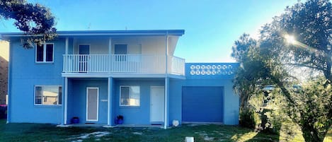 A two-story residential building with a balcony, a garage, and a well-maintained lawn.