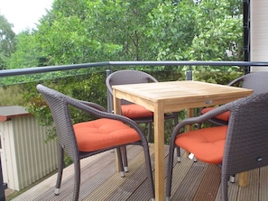 A balcony with wicker furniture and orange cushions, overlooking a lush green area. - Muhlenstrasse 19 Apartment 4 (Zingst)
