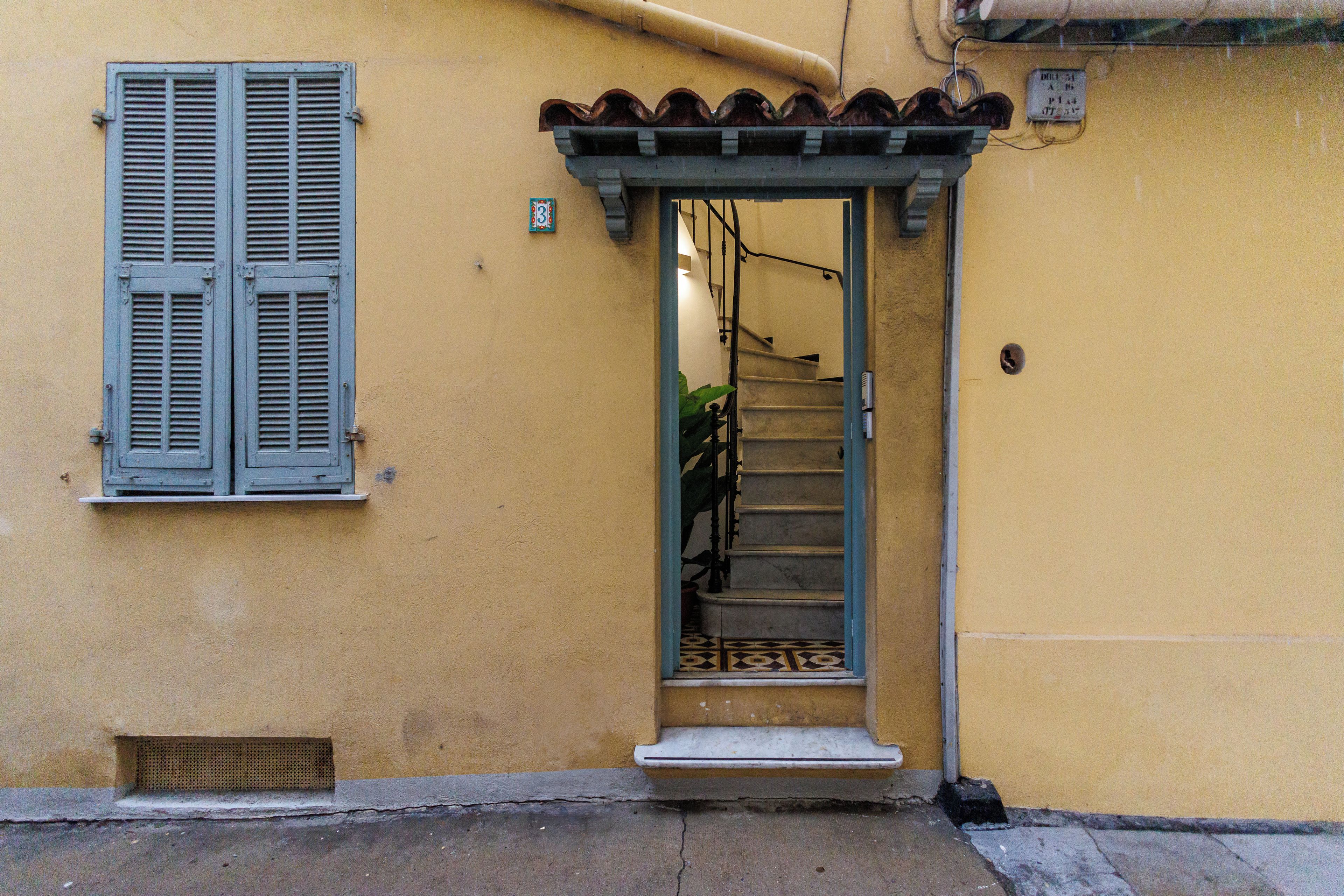 A yellow building with a door leading to a staircase.