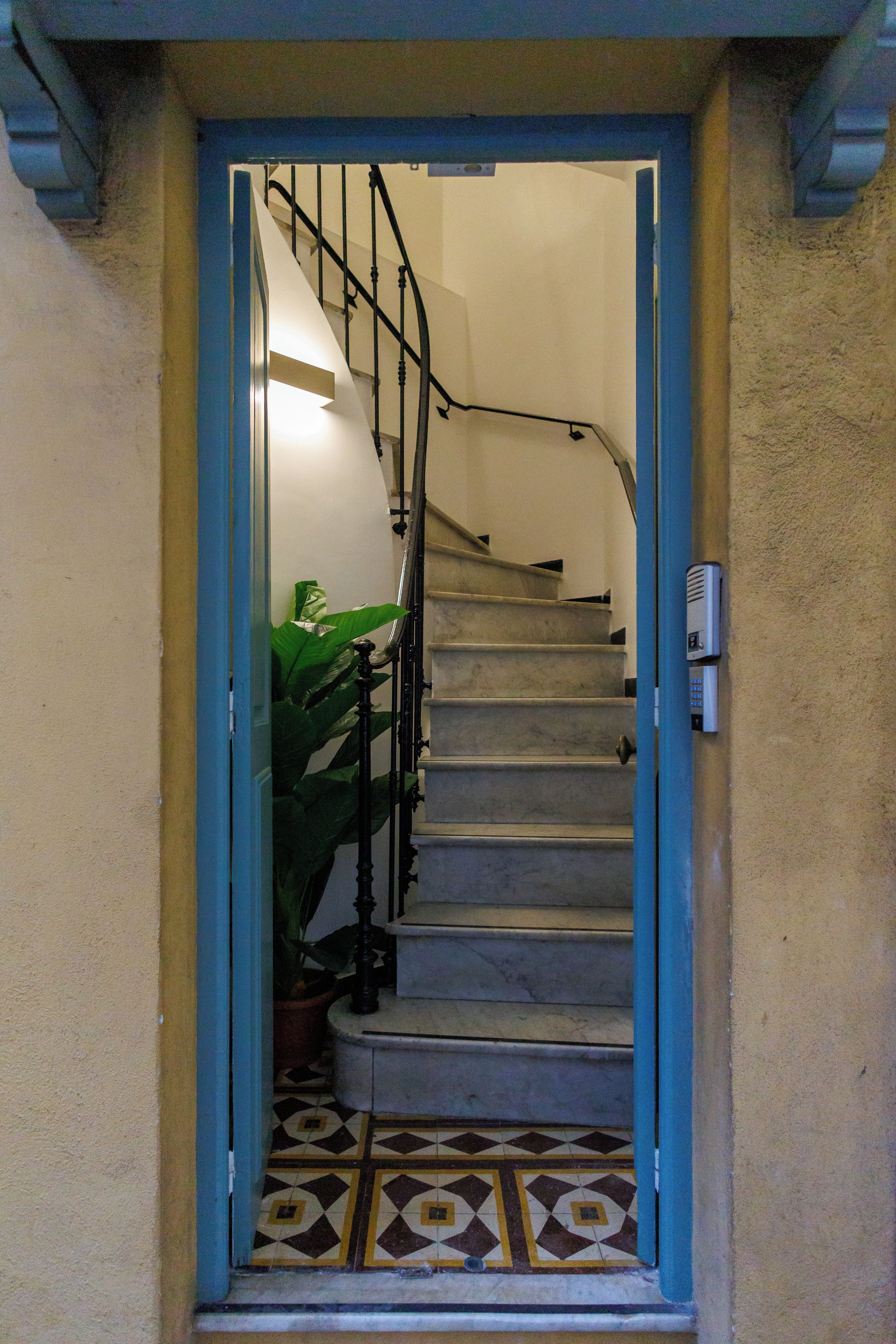 Un escalier menant à l’étage supérieur, avec une rampe et une porte en bas.
