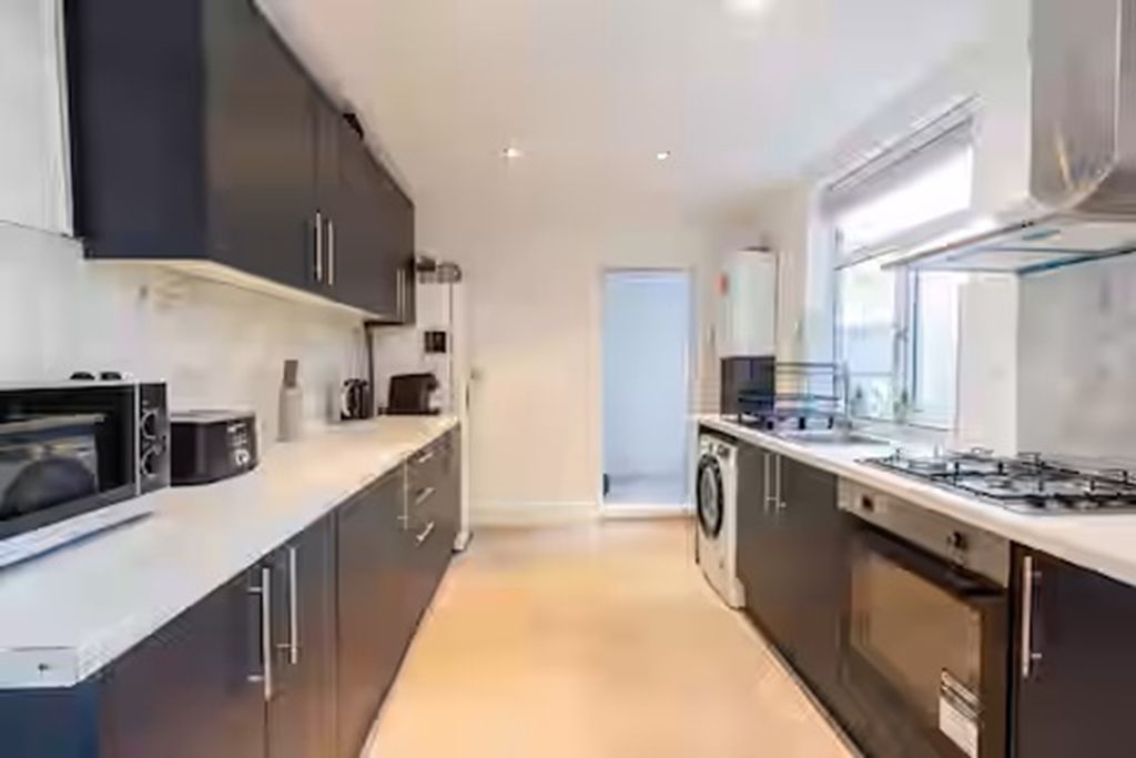 A modern kitchen with dark cabinetry, a built-in oven, a microwave, and a gas stove.