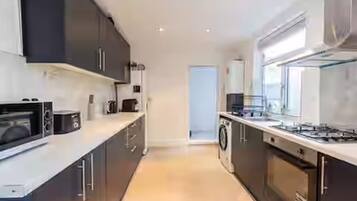 A modern kitchen with dark cabinetry, a built-in oven, a microwave, and a gas stove.
