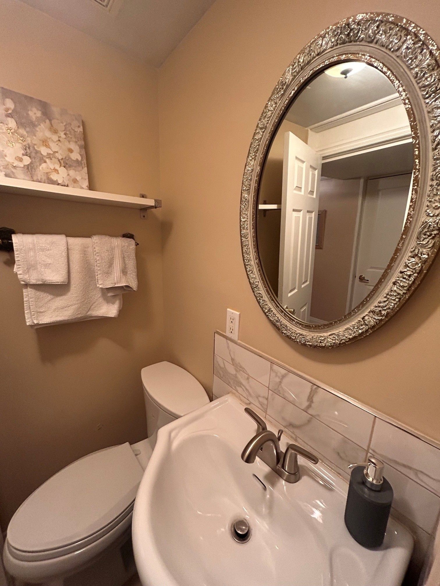 A bathroom with a toilet, a sink, a mirror, and a towel rack.