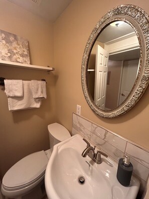 A bathroom with a toilet, a sink, a mirror, and a towel rack.