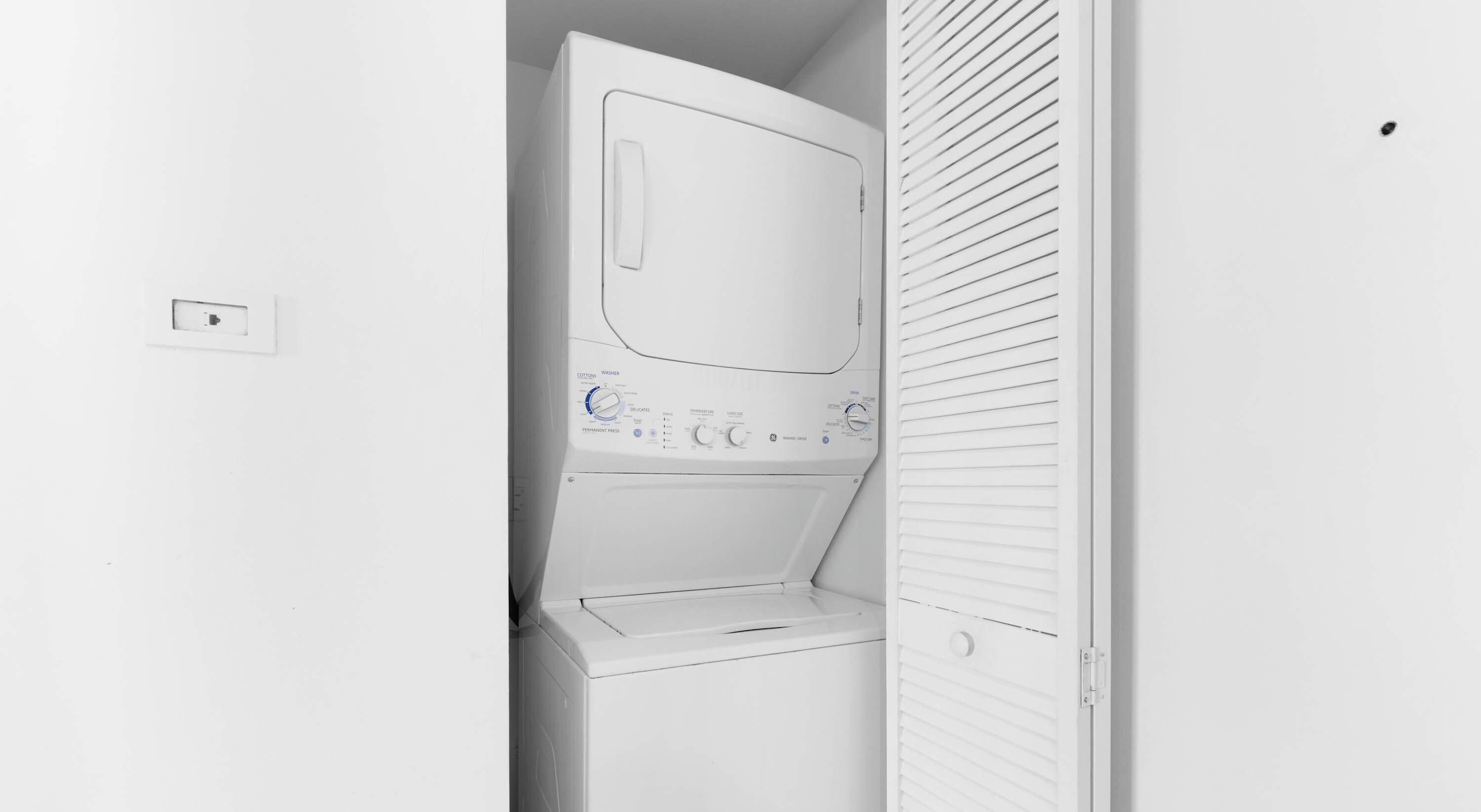 A laundry room with a washing machine and dryer, a control panel with various settings, and a door with a handle.