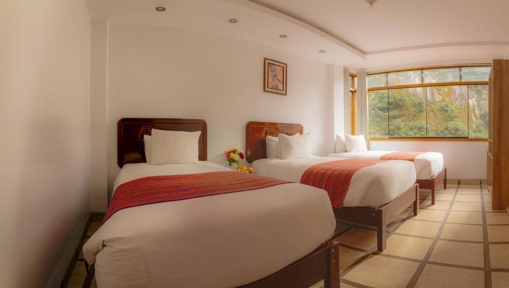 Habitación de hotel con dos camas, un ventanal con vistas a la vegetación y un cuadro en la pared.