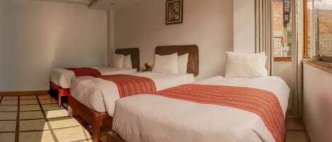 A hotel room with two beds, a window with curtains, and a view of the outside.