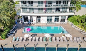 A modern hotel with a rooftop pool, sun loungers, and a swan float. - Modern APT w/ Panoramic Intracoastal 2BR High Floor (Hallandale Beach)