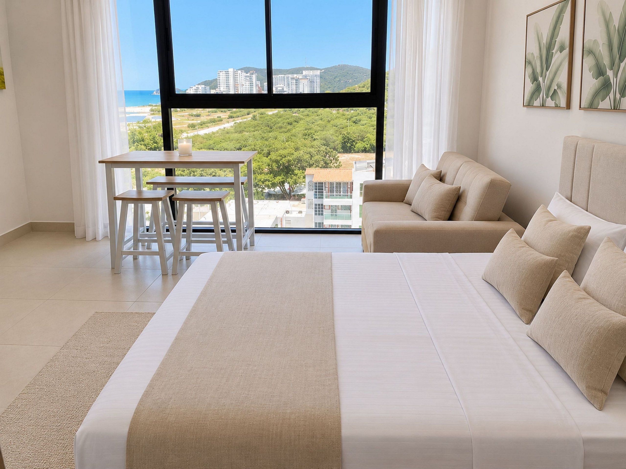 Une chambre moderne avec un grand lit, un canapé, une table à manger et une vue sur le paysage urbain grâce à de grandes fenêtres.