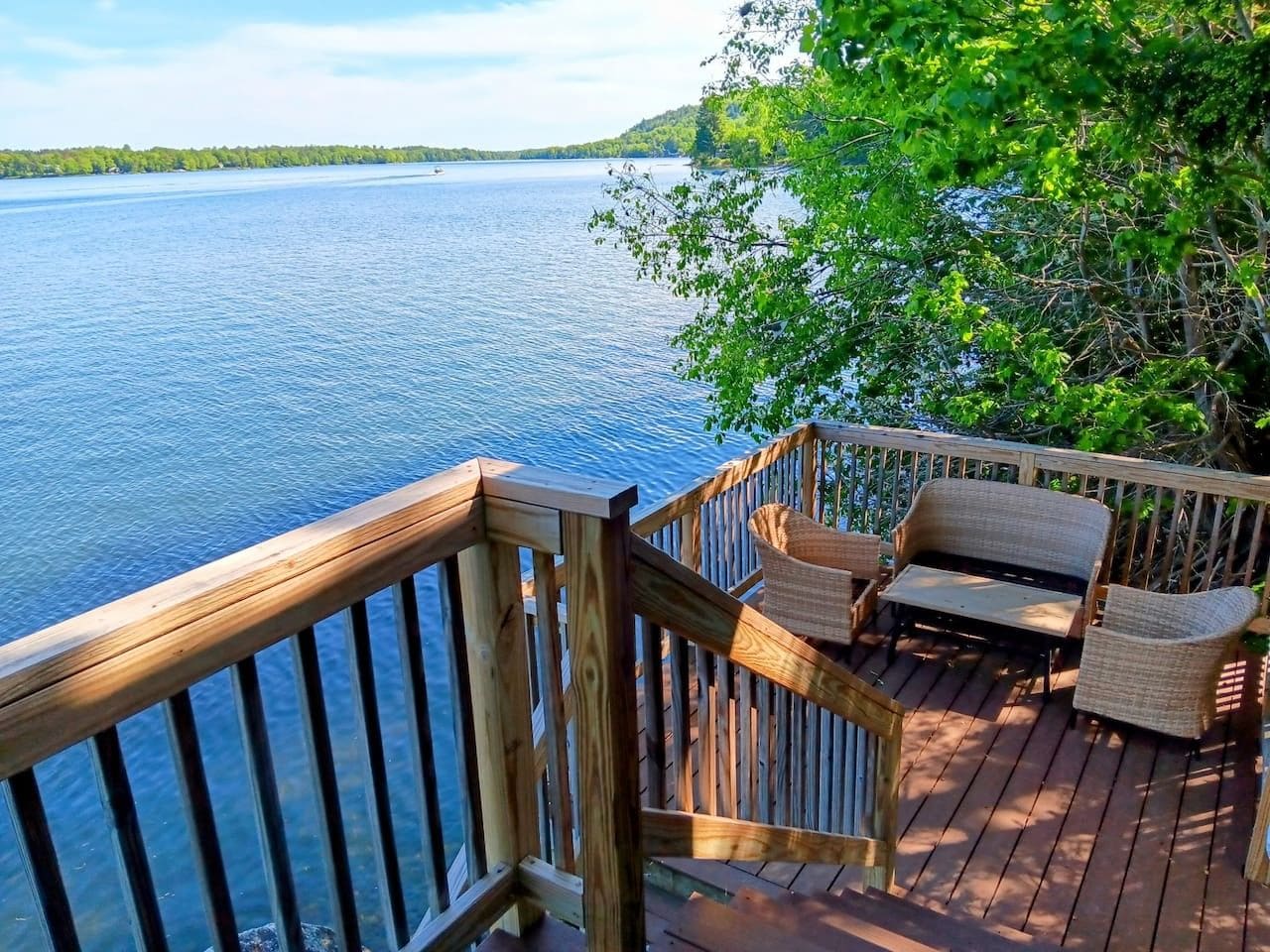 A wooden deck with wicker furniture overlooking a body of water.