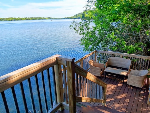 A wooden deck with wicker furniture overlooking a body of water.