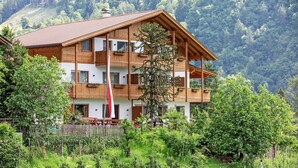 A multi-story wooden building with balconies, surrounded by lush greenery and a mountainous backdrop. - Apartment Innermoarhof Ifinger with Mountain View, Shared Garden and Wi-Fi (Rifiano)