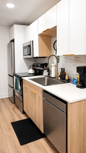 Een moderne keuken met roestvrijstalen apparatuur, houten kastjes en een zwart vloerkleed.