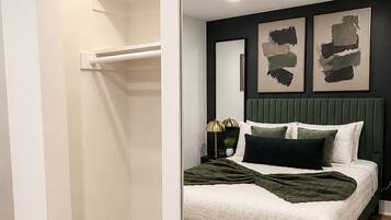 Een slaapkamer met een bed, nachtkastjes, een spiegel en kunst aan de muur.