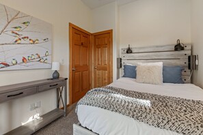 A bedroom with a bed, bedside table, lamp, and a wall-mounted lamp. - Bottle Bay Beauty | Lake Views Near Sandpoint (Sagle)