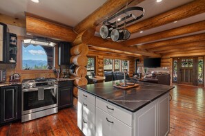Een ruime keuken met moderne apparatuur, een groot eiland en uitzicht op de bergen.