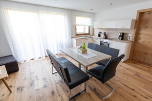Eine moderne Küche mit Essbereich, Holzboden und einem großen Fenster.