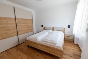Ein Schlafzimmer mit einem hölzernen Bett, weißen Wänden und einem Holzboden.