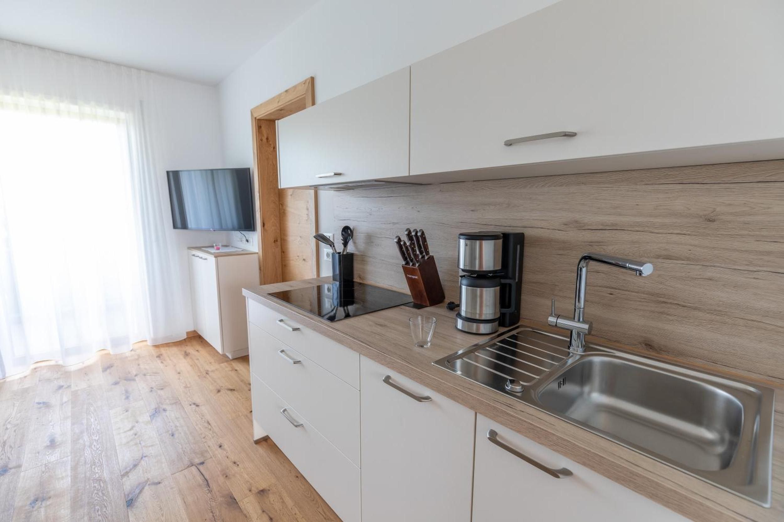 A modern kitchen with a wooden countertop, stainless steel sink, and a coffee maker.