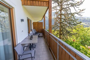 Ein Balkon mit Tisch und Stühlen mit Blick auf eine gebirgige Landschaft.