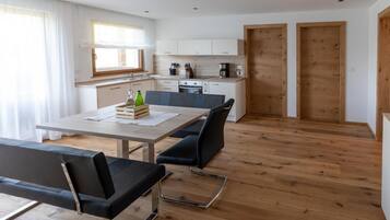 A modern kitchen with white cabinets, a dining table, and two black chairs.