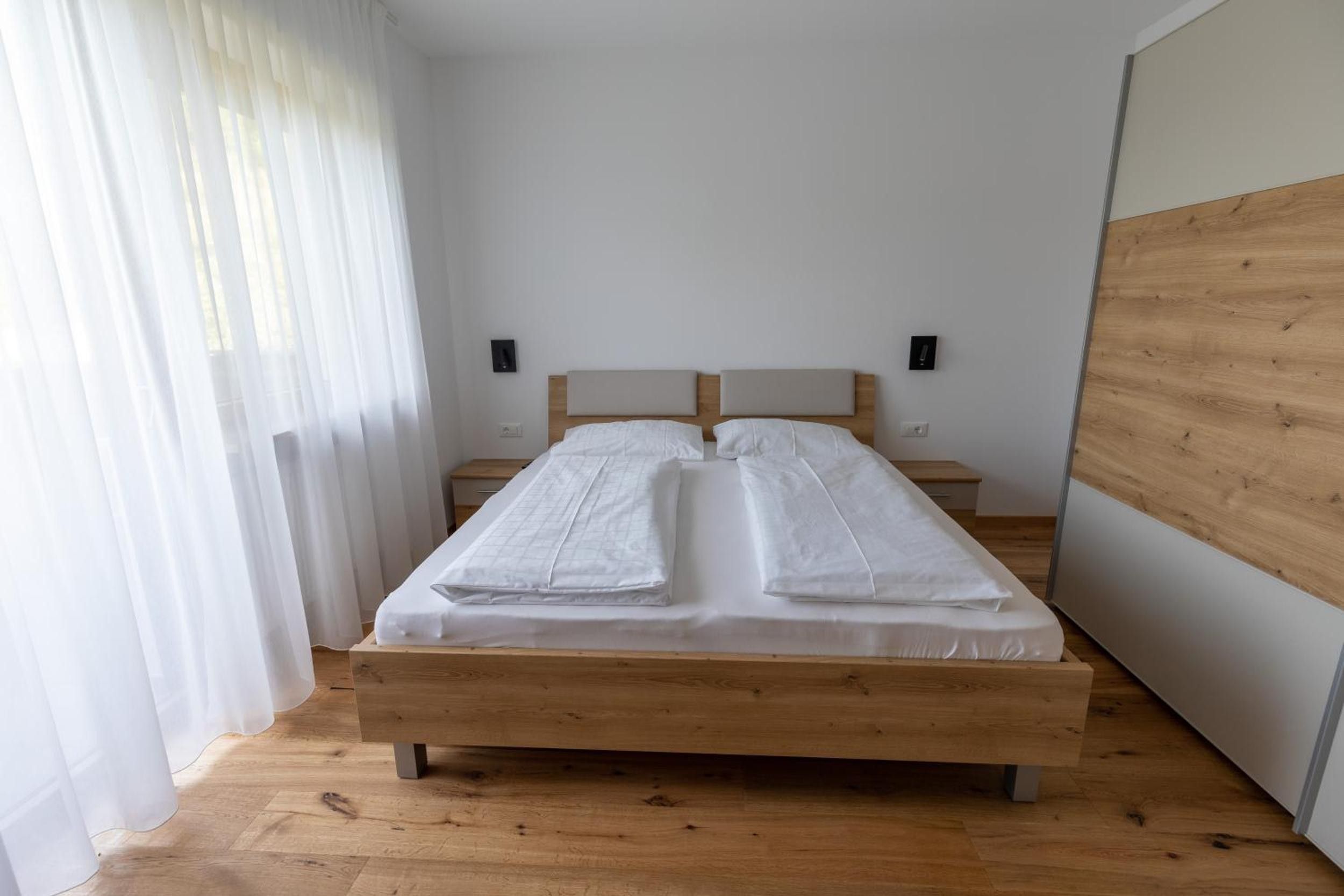 A single bed with a wooden frame and headboard, positioned against a white wall with two wall-mounted nightstands.
