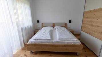 A single bed with a wooden frame and headboard, positioned against a white wall with two wall-mounted nightstands.