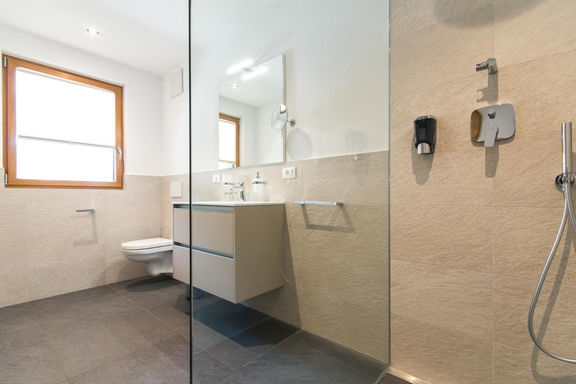A modern bathroom with a glass shower enclosure, a toilet, and a sink.