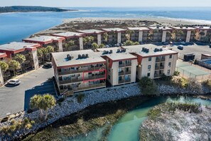 Ein mehrstöckiges Hotel mit Balkonen, einem Parkplatz und Blick auf den Strand.