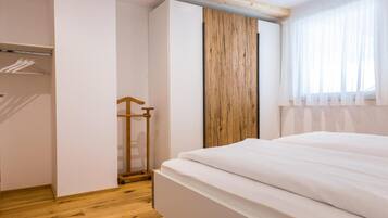 Un dormitorio con una cama, un armario de madera y un ventanal con cortinas.