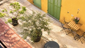Une terrasse avec une table et des chaises, des plantes en pot et un mur jaune.