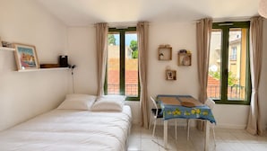 Une chambre à coucher avec un lit, une table avec des chaises et une fenêtre avec des rideaux.