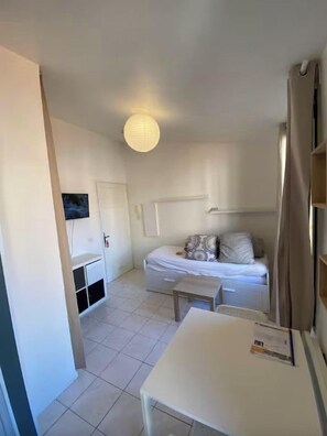 A bedroom with a bed, bedside table, and a white wardrobe.