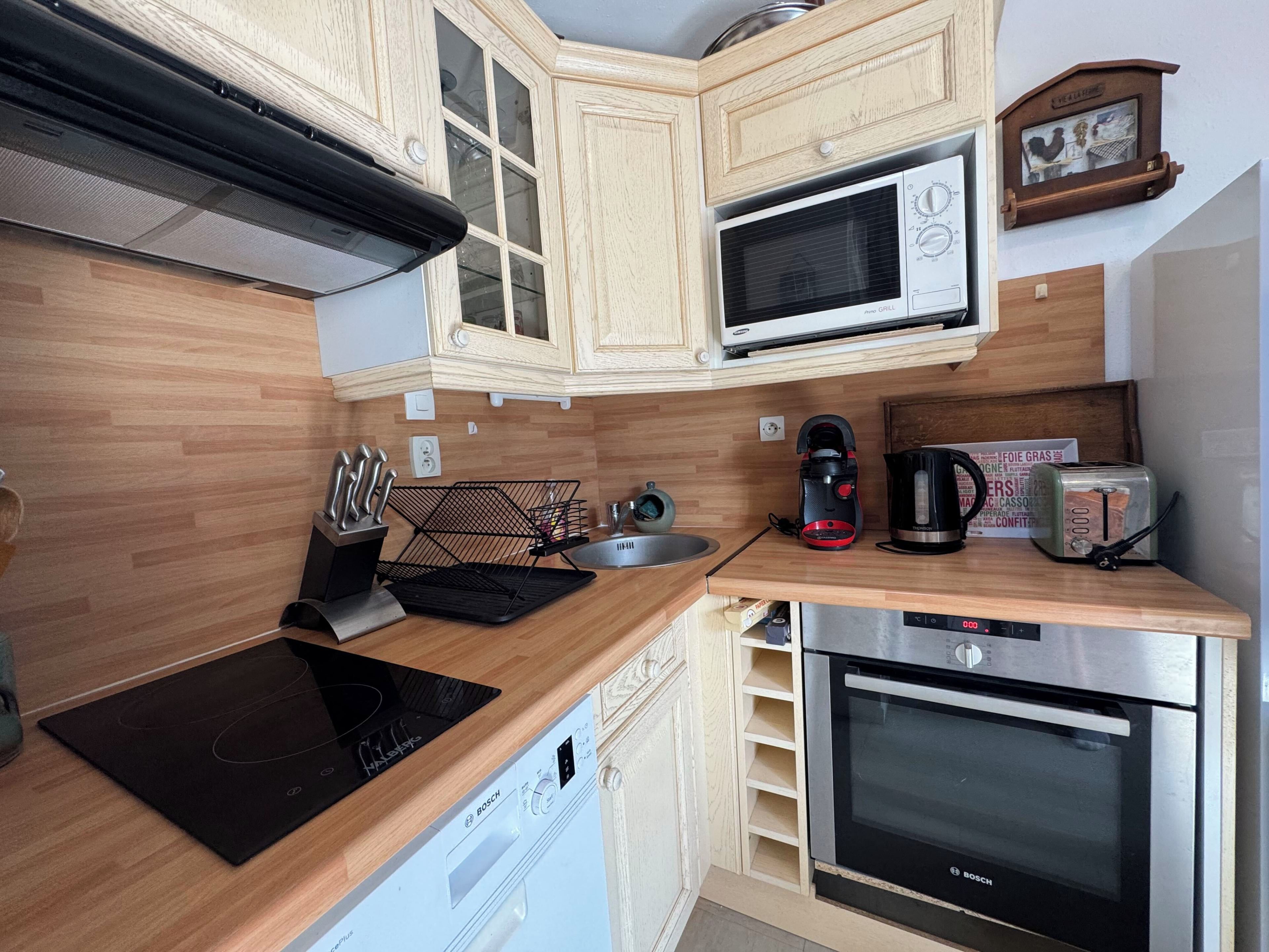 A kitchen with wooden cabinets, a Bosch dishwasher, a microwave, a toaster, and a coffee maker.