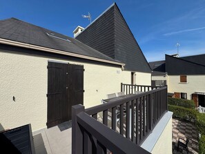 A residential building with a sloped roof, a balcony with a railing, and a small garden area. - Duplex with terrace near beach (Merville-Franceville-Plage)