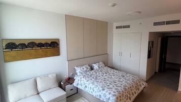 A modern bedroom with a bed, bedside table, nightstand, and a sofa.