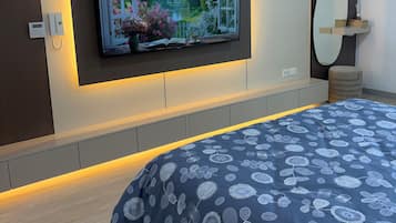 Ein modernes Schlafzimmer mit einem großen Bett, einem an der Wand befestigten Fernseher und einer eingebauten Ablage.