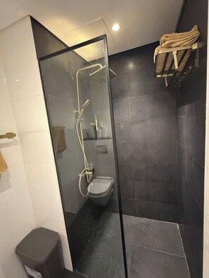 Un baño moderno con ducha envuelta en vidrio, inodoro y toallero.