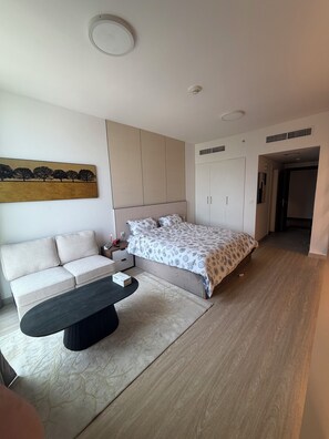 Un dormitorio moderno con cama, sofá, una mesita de centro y un cuadro en la pared.