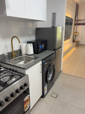 Una cocina moderna con estufa a gas, lavadora, microondas y refrigerador.