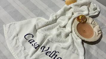 A white towel with 'Casa Velha' embroidered on it, placed on a striped surface.
