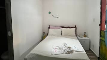 A single-bed room with a wooden ceiling, a bedside table, a nightstand, and a hanging light fixture.