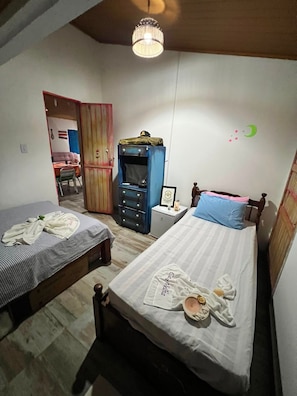 Quarto com duas camas, um guarda-roupa, uma escrivaninha e um candeeiro suspenso.