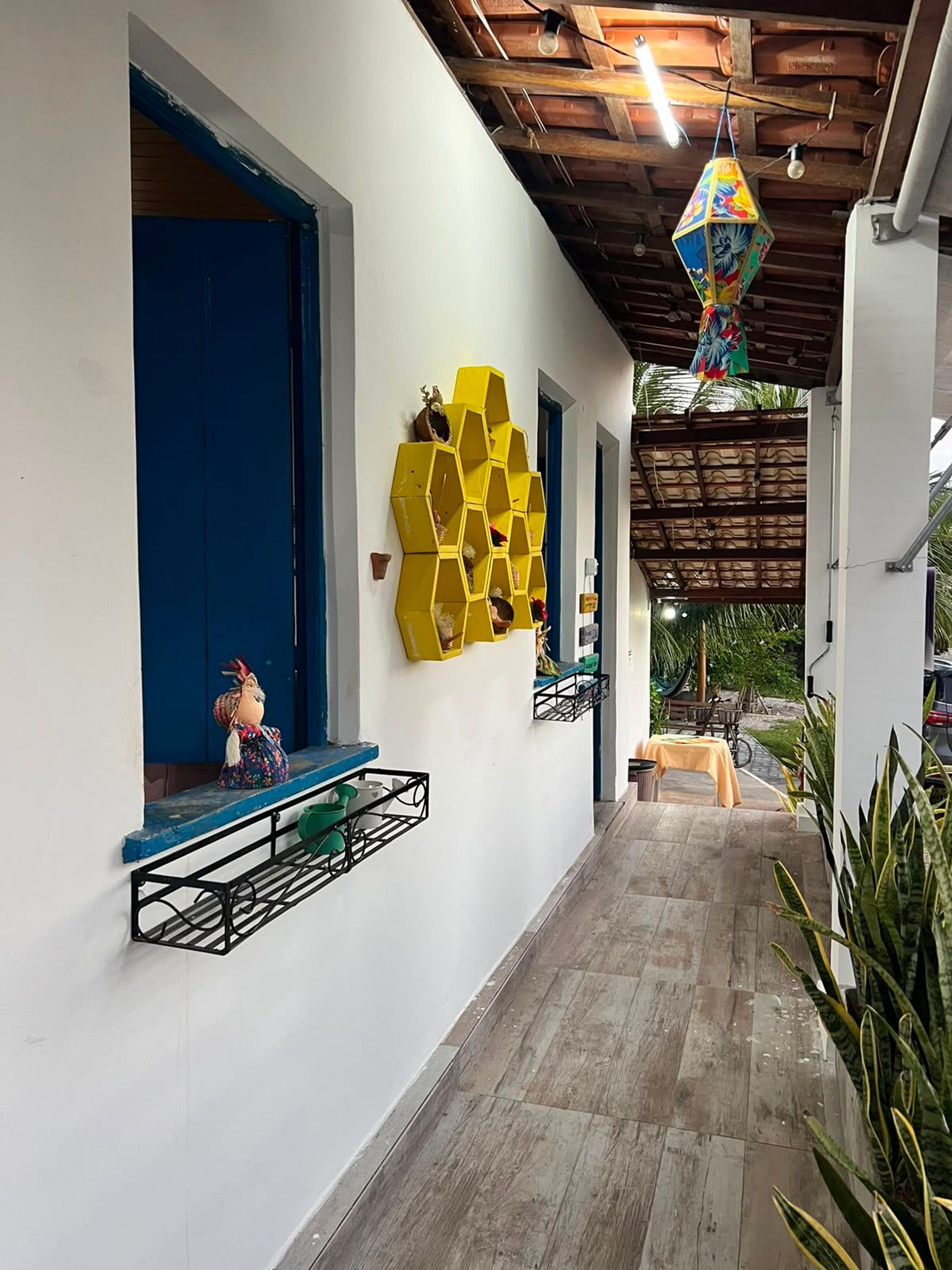 Un pasillo con una puerta azul, un estante hexagonal amarillo y un adorno colgante.
