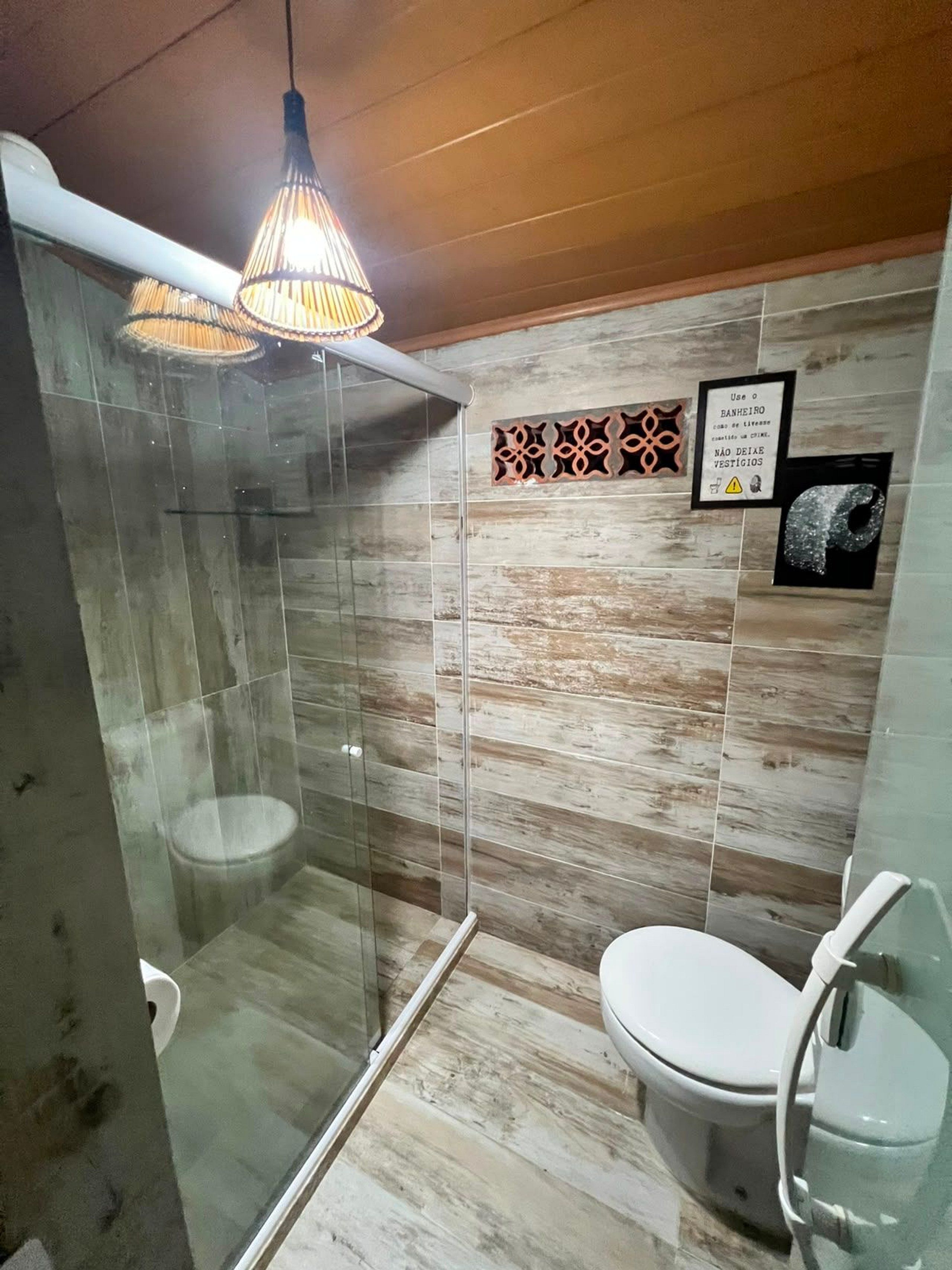 Ein Badezimmer mit Duschkabine, Toilette und einer Hängeleuchte.