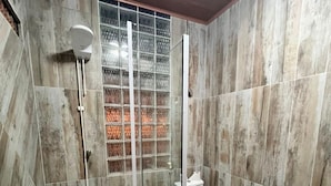 A bathroom with a glass-enclosed shower, a toilet, and a checkered mat. - Casa Velha Hospedagem Jacuípe (Camaçari)