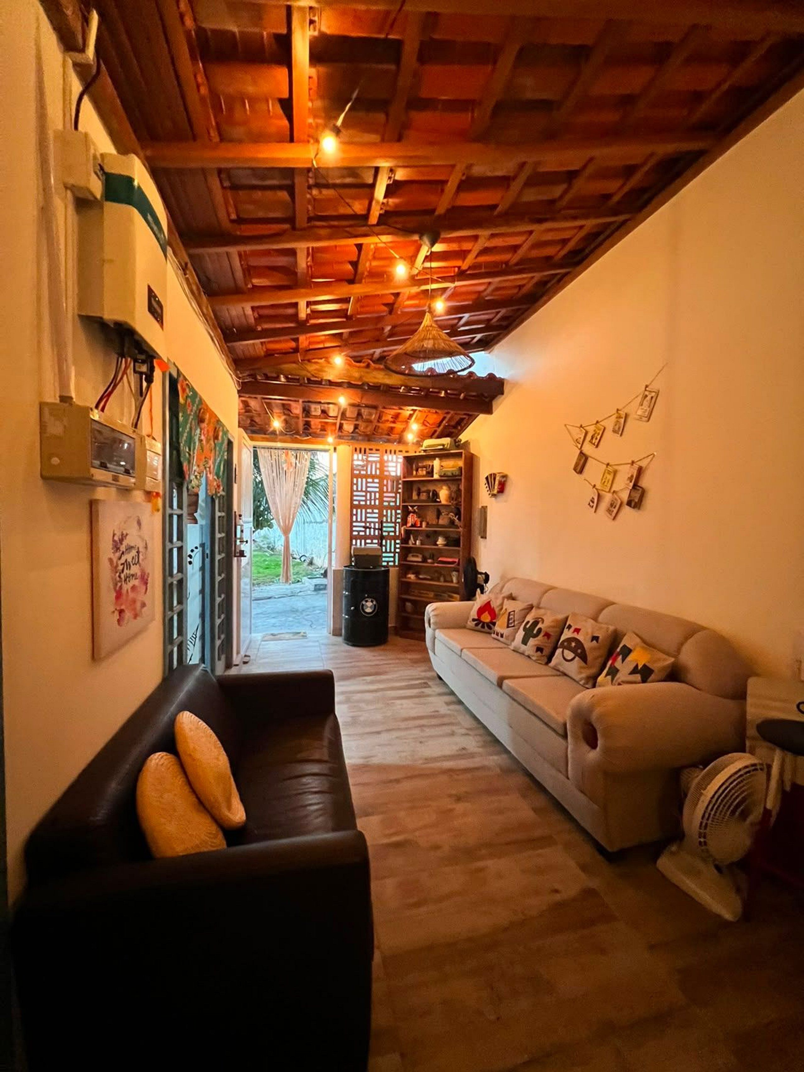 Una sala acogedora con techo de madera, un sofá, un sillón de cuero negro y un ventilador.