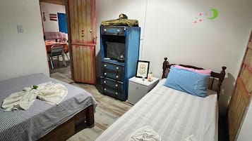Ein Schlafzimmer mit zwei Betten, einem Kleiderschrank, einem Schreibtisch und einer Pendelleuchte.